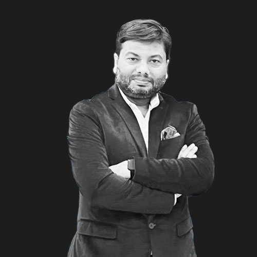 Man in black suit with arms crossed standing in an office environment